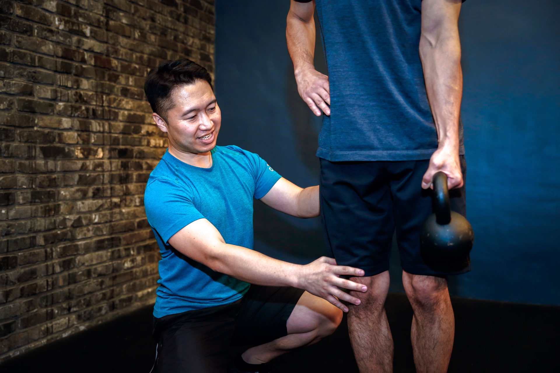 森川稔之が片膝立ちで膝に手を添え立位の動きを指導する